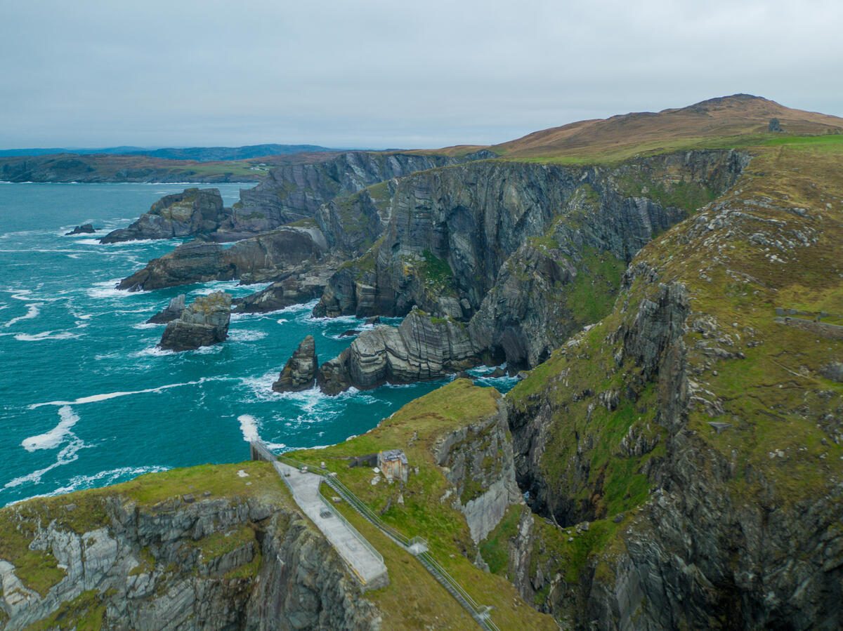 The arched concrete footbridge to Mizen Head Signal Station, with sea stacks and Atlantic cliffs along the West Cork coast