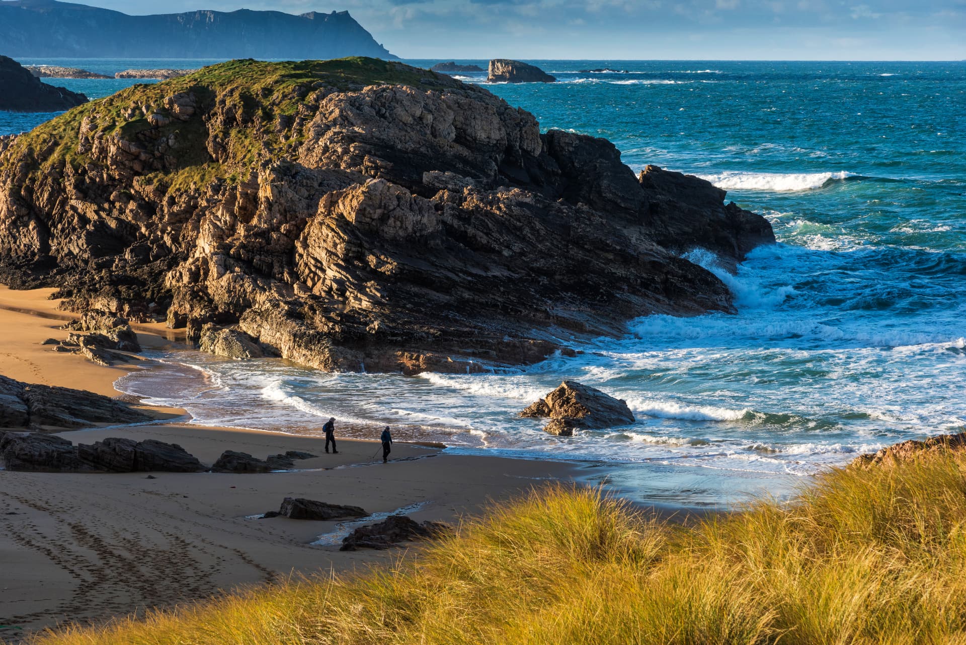 Murder Hole Beach (Boyeeghter Bay) in County Donegal, with golden sand, dark rocks and Atlantic waves below dune grass