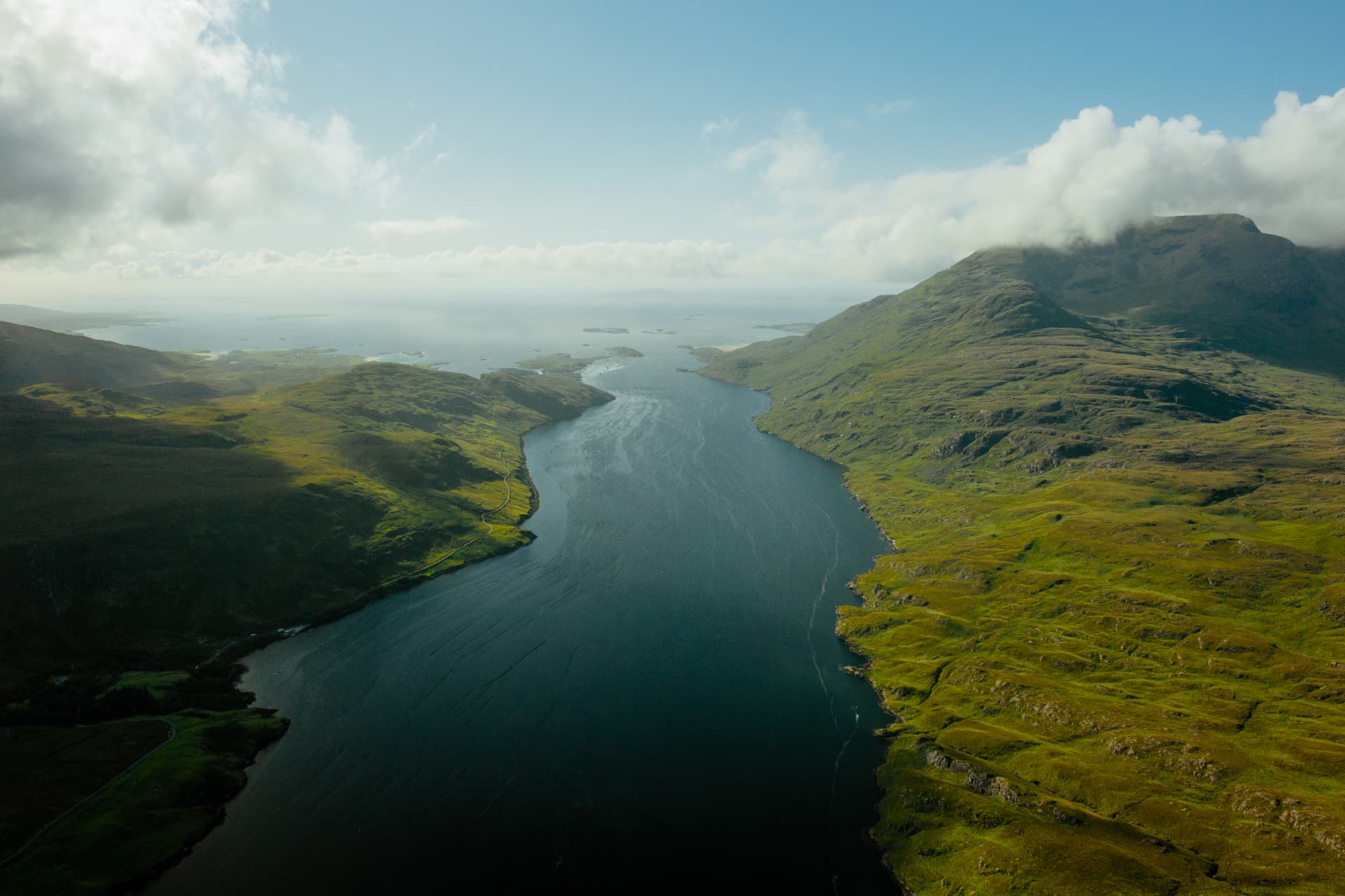 Aerial view of Killary Fjord, with dark-blue water between green mountain slopes and low islands toward the Atlantic mouth