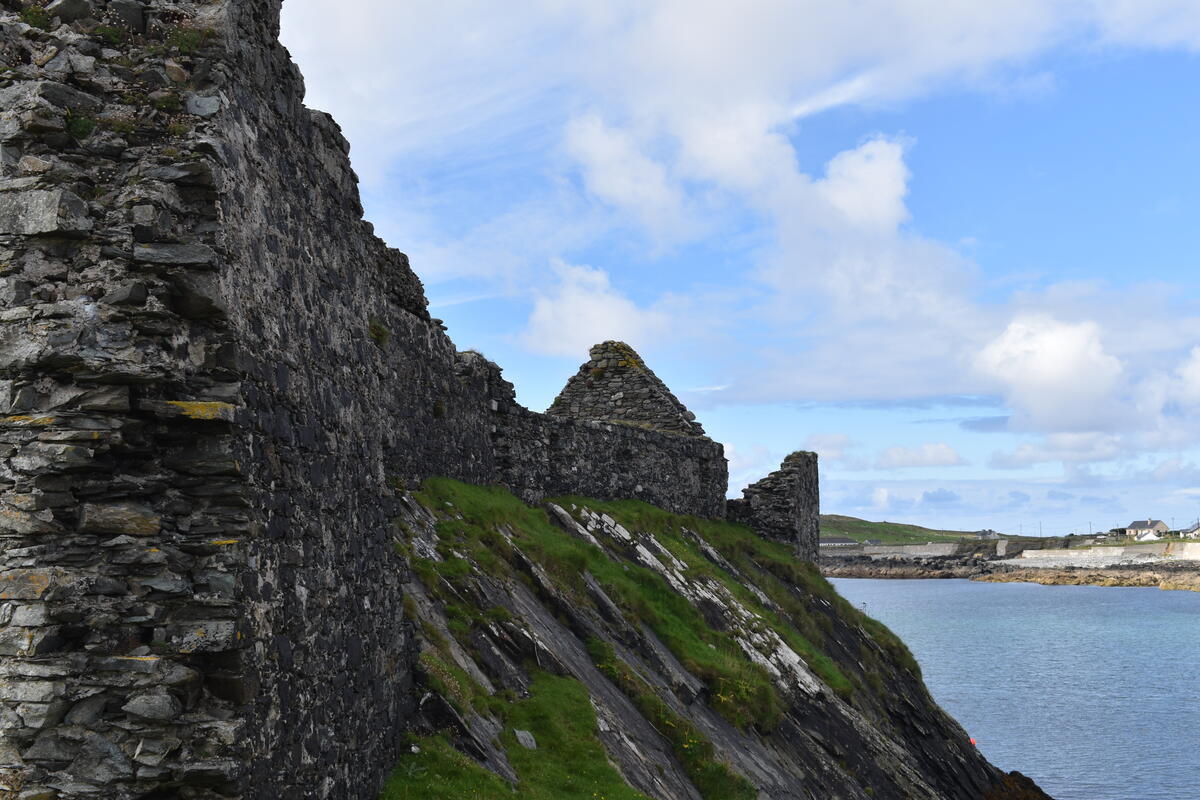 Stone ruins on Inishbofin overlooking a sheltered Atlantic bay with the Connemara mountains in the distance